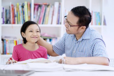 Genç erkek öğretmen öven ve onun öğrenci başkanı kütüphanede otururken okşamaya görüntüsünü 