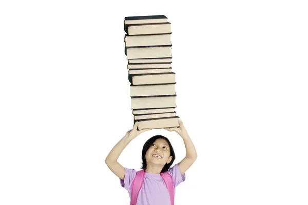 Фото Милой Школьницы Поднимающей Стопку Книг Стоящей Студии Белом Фоне — стоковое фото