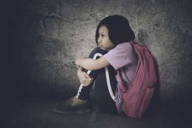 Stres ifade ile katta otururken bir sırt çantası taşıyan liseli kızlar resmi