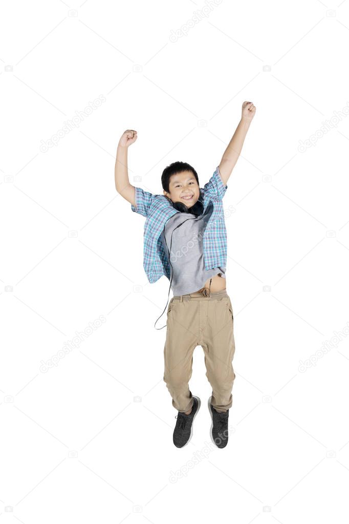 Portrait of handsome preteen student looks happy while jumping in the studio, isolated on white background