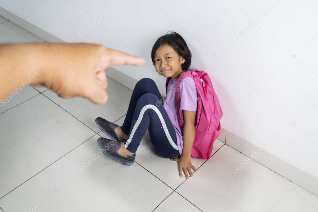 Picture of cry schoolgirl being scolded by her teacher while sitting on the classroom floor