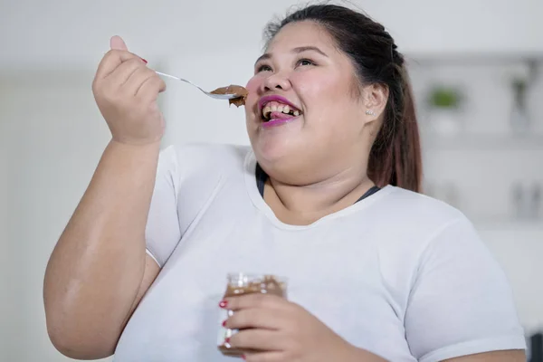 亲密的快乐超重的女人吃巧克力奶油与茶匙在厨房 — 图库照片