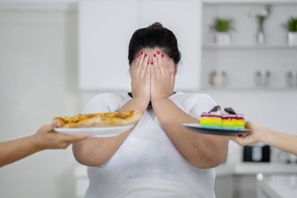 超重的妇女闭上眼睛试图避免垃圾食品 — 图库照片