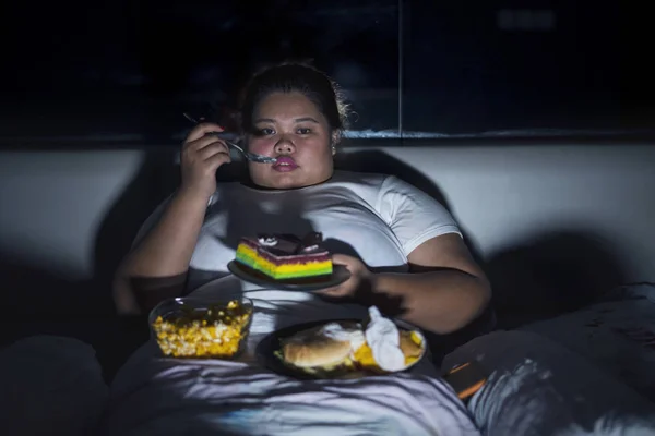 不健康なライフ スタイル コンセプト 寝る前にベッドでジャンク フードを食べて太りすぎの女性 — ストック写真