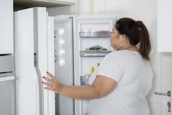 Толстая Женщина Открывает Холодильник Кухне — стоковое фото