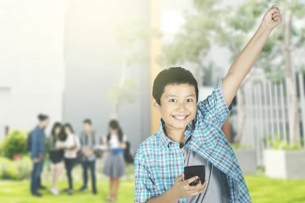 Изображение Мальчика Подростка Использующего Смартфон Время Празднования Успеха Поднимающего Руку — стоковое фото