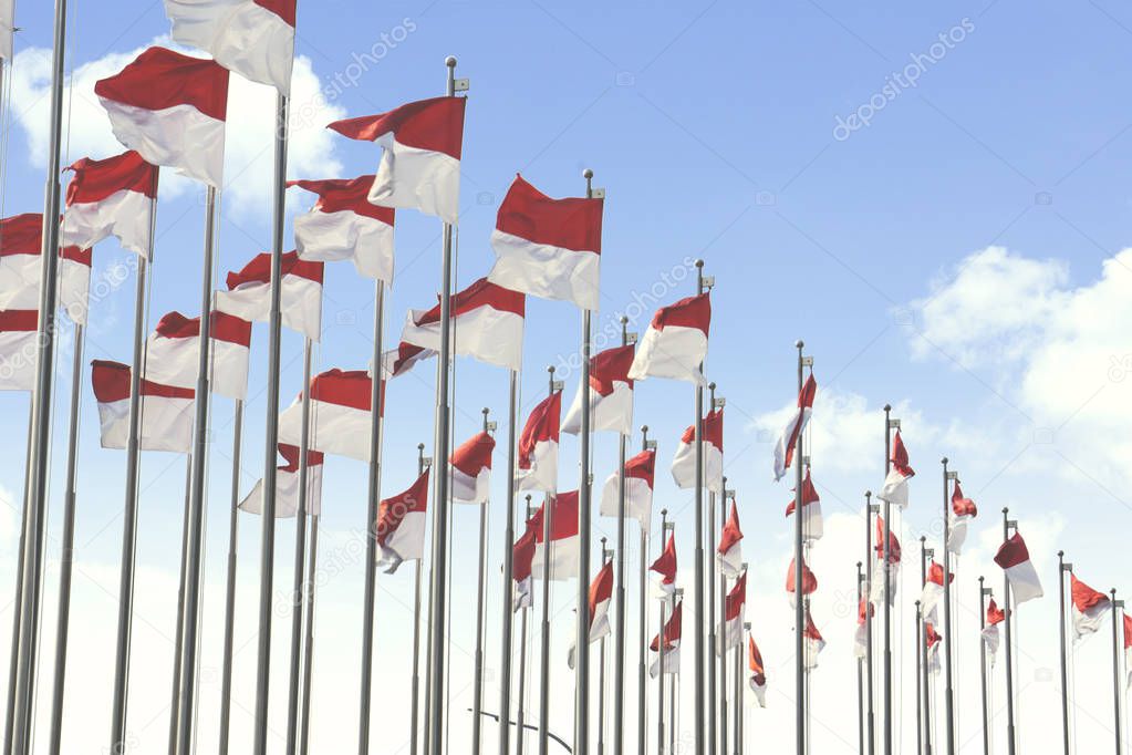 Image of national flags of Indonesia flying on the flagstaff with blue sky background