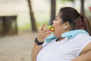 Kilolu kadın sabah egzersiz sırasında istirahat ederken çörek yeme