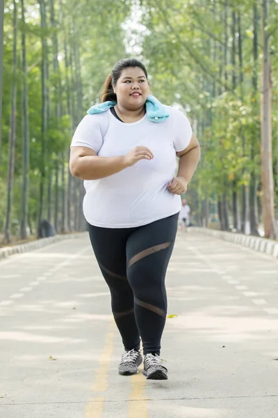 道をジョギングしながら運動をしている太りすぎの女性のイメージ — ストック写真