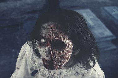 Halloween korku kavramı. Bir korkunç zombi kadın closeup mezarlıkta kameraya bakıyor