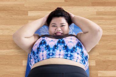 Asyalı şişman kadın karın sit yaparken kameraya gülümseyen görünümünü yüksek açı ups fitness merkezinde 