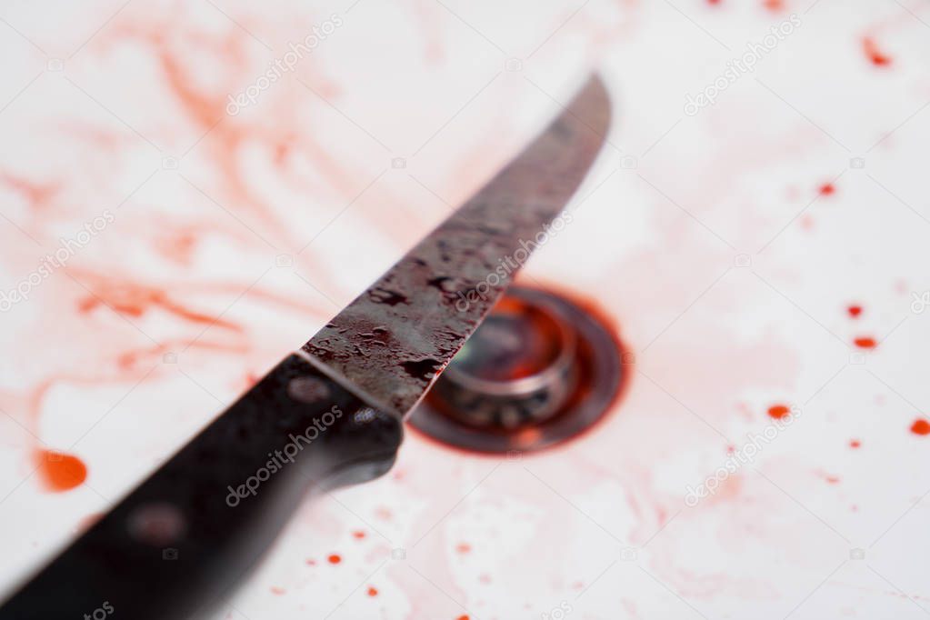Closeup of bloody knife with splattered blood in the sink. Concept of Halloween horror