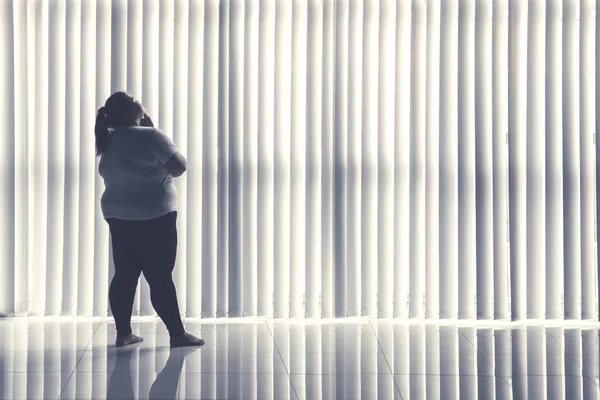 站在家里的胖女人的背上做白日梦的窗口 — 图库照片