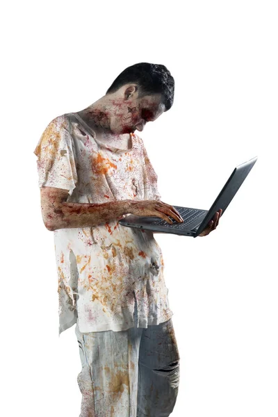 照片的可怕的男性僵尸使用笔记本电脑 而站在演播室 在白色背景隔离 — 图库照片