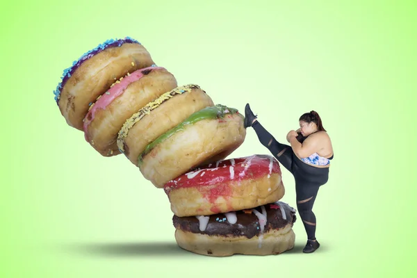 一张胖女人的照片 她拒绝吃甜食 踢了一堆甜甜圈 绿色屏幕背景拍摄 — 图库照片
