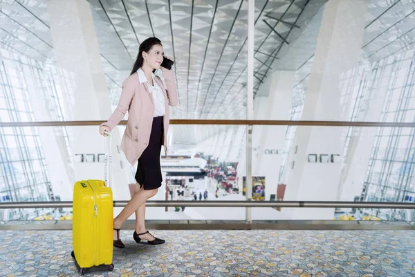 白人女商人在机场拿着手提箱在手机上聊天 — 图库照片