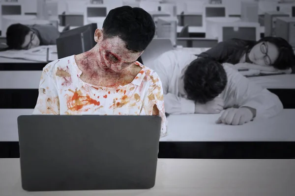 Picture of zombie man working overtime in the office with his exhausted friends