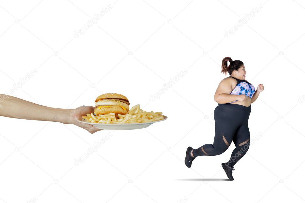 Portrait of Asian obese woman looks scared while running from fast food offered, isolated on white background