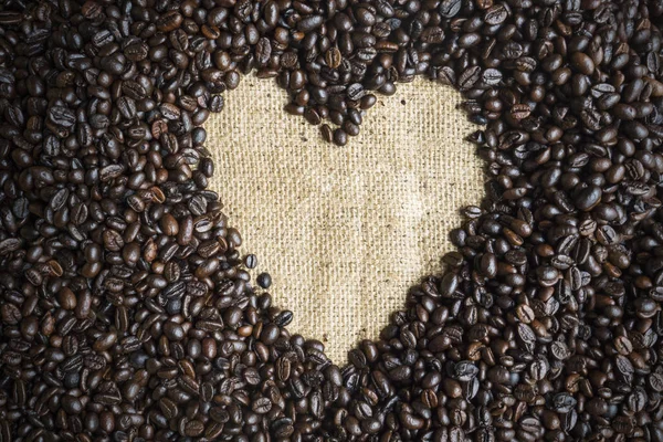 ヒープ コーヒー豆黄麻布の上にハート形の上から見る — ストック写真