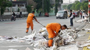 Jakarta - Endonezya. 18 Eylül 2018: Eid Al Bayramı kutlama sonra çöp sokaktan süpürmek için bir süpürge kullanarak iki süpürgeler