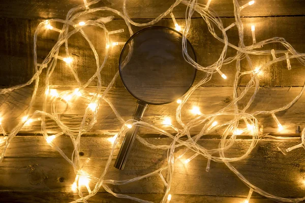 Увеличительный Стеклянный Снимок Рождественскими Огнями Старинном Деревянном Фоне — стоковое фото