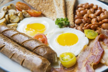 Sosis, yumurta, kızarmış ekmek, fasulye ve mantar plaka ile kızarmış domuz pastırması closeup