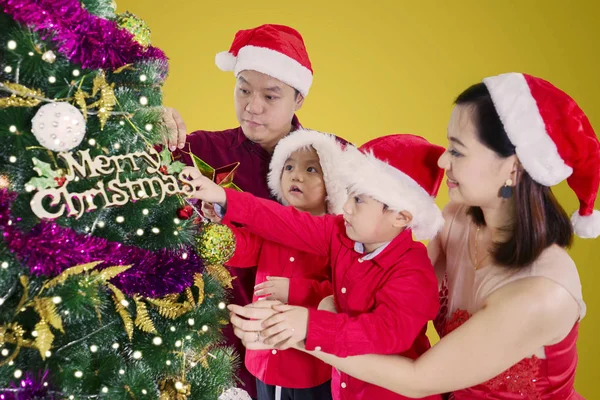 Asiatische Familie Schmückt Gemeinsam Einen Weihnachtsbaum Und Trägt Dabei Eine — Stockfoto