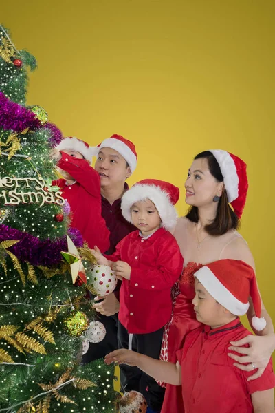 三儿童在与父母装饰圣诞树时戴着圣诞老人的肖像 — 图库照片