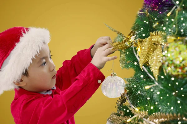 Niedlicher Kleiner Junge Mit Weihnachtsmütze Der Hause Eine Weihnachtskugel Weihnachtsbaum — Stockfoto