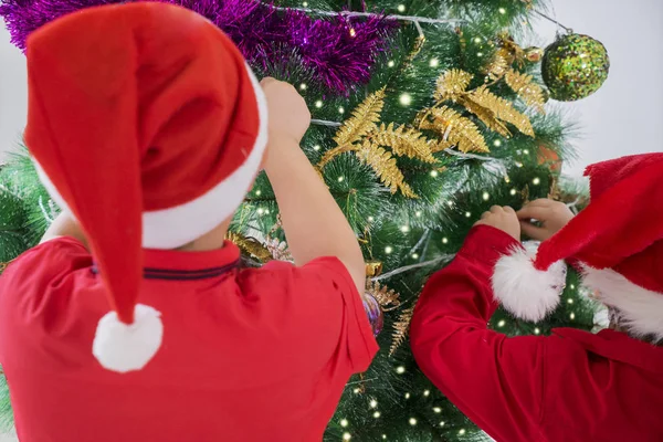 Visão Traseira Duas Crianças Decorando Uma Árvore Natal Juntas Casa — Fotografia de Stock