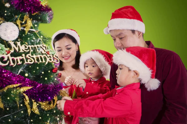 快乐亚洲家庭装饰圣诞树 同时戴着圣诞帽 — 图库照片