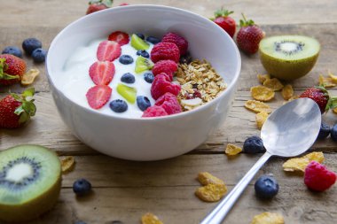 Portre sağlıklı kahvaltı ile yulaf ezmesi, taze meyve ve yoğurt bir kase. Ahşap masaya vurdu