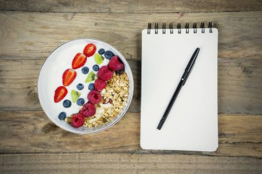 Üstten görünüm boş kağıt notlar çilek ve bir kase mısır gevreği. Ahşap masaya vurdu