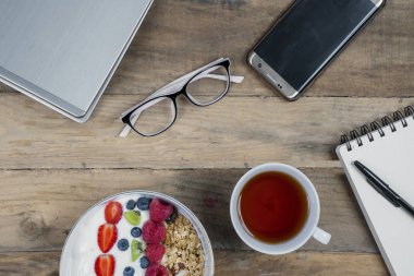 Tahıl ve ahşap masa üzerinde sıcak çay ile yüksek açılı görünüş ofis malzemeleri