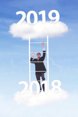 Genç işadamı yukarı merdiven ile 2018 numaradan numarasına 2019 mavi gökyüzünde tırmanma