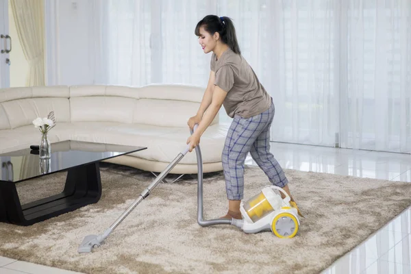 亚洲妇女清洁地毯用吸尘器在客厅里 在家拍摄 — 图库照片