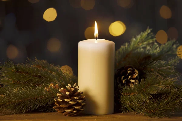 枝と輝く明るい背景をぼかした写真の木製のテーブルの上の松ぼっくりクリスマス キャンドル — ストック写真