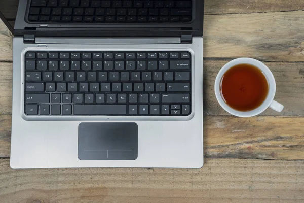 木製のテーブルに紅茶のカップでラップトップ コンピューターの平面図 — ストック写真