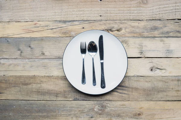 鉄鋼スプーン フォーク ナイフの木製のテーブルと陶板のクローズ アップ — ストック写真