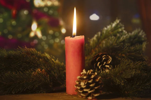 Rote Kerze Mit Tannenzweigen Und Zapfen Auf Verschwommenem Christbaumhintergrund — Stockfoto