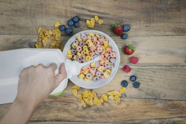 Donna Sconosciuta Versando Latte Una Ciotola Cereali Con Bacche Sul — Foto Stock