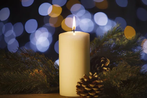 关闭的白色蜡烛 杉木树 和松树锥上的桌子上模糊的圣诞灯光背景 — 图库照片