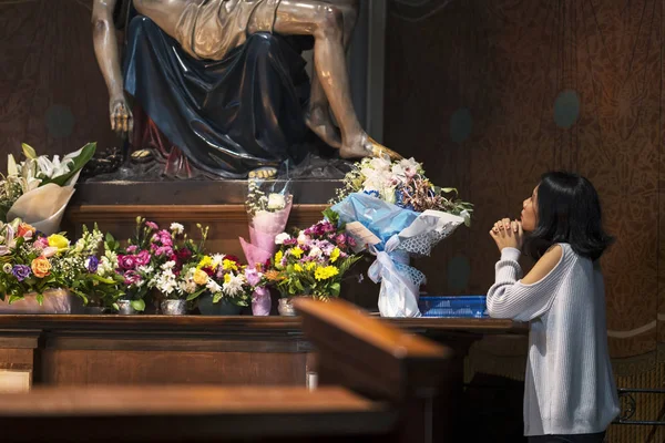 Picture of young woman begging forgiveness to God while praying near church altar