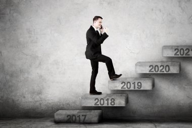 Beyaz işadamı merdiven üzerinde sayı 2019 doğru yürürken bir akıllı telefon konuşma