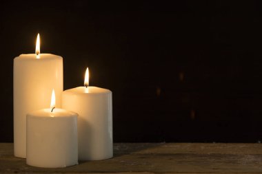 Koyu arka plan kopya alanı ile ahşap masa üzerinde parlayan Noel mumlar