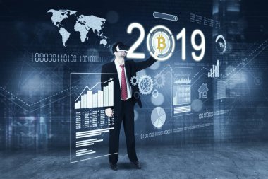 Genç işadamı bir sanal gerçeklik dokunaklı bitcoin sembolü ise sanal ekran üzerindeki 2019 numarasıyla gözlükle