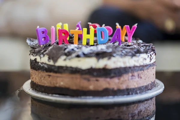 巧克力生日蛋糕与五颜六色的蜡烛问候在家里的桌子上 — 图库照片
