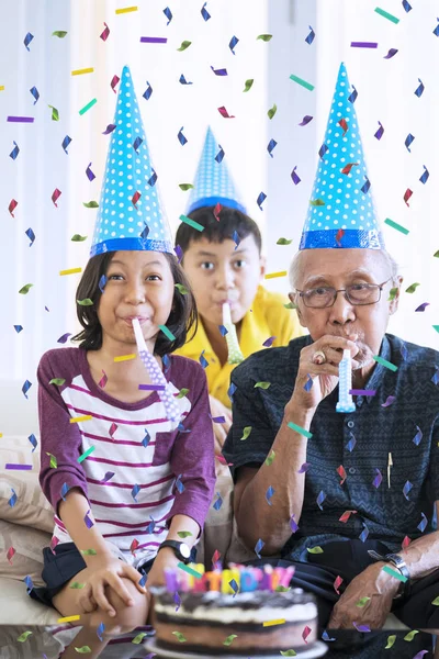 自宅落ちる紙吹雪の誕生日帽子を着用しながら彼らの祖父の誕生日を祝う幸せ孫 — ストック写真