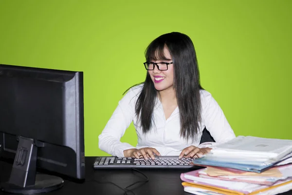 亚洲女实业家的图片打字在电脑键盘 而坐在工作室与绿色屏幕 — 图库照片