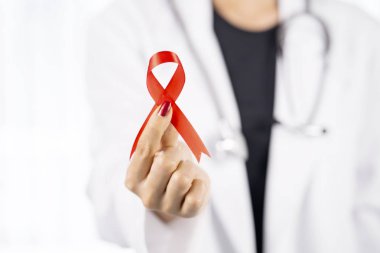 Kırmızı kurdele gösterilen genç kadın doktor closeup. Dünya AIDS Günü kavramı